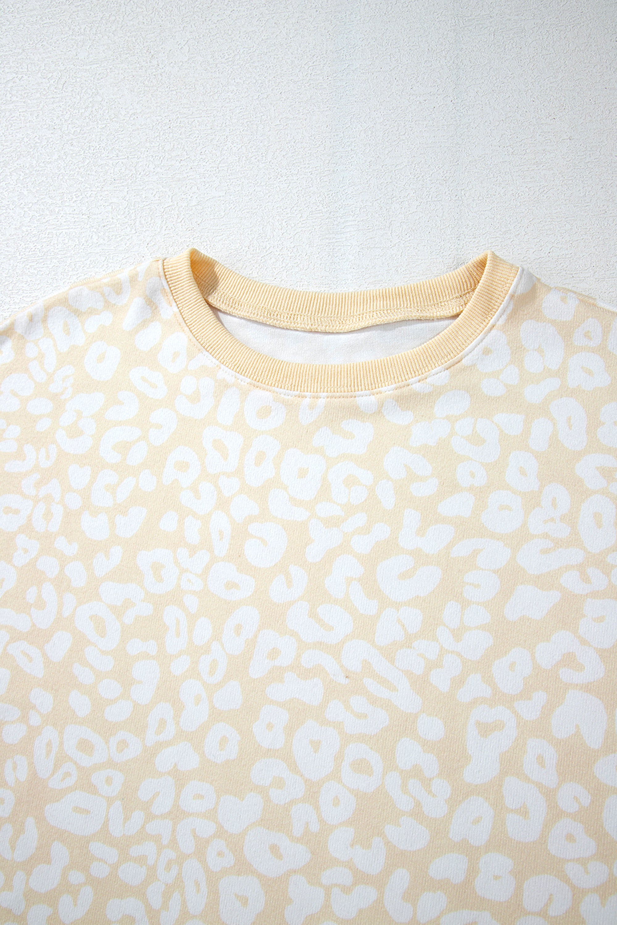 طقم نسائي قطعتين، مكون من بلوزة وبنطلون، لونه أبيض بنقشة الفهد باللون الذهبي المطفي. مصمم لراحتك بقصة فضفاضة وحزام خصر قابل للتعديل، ويتميز بتموجات جميلة على طرف البلوزة.