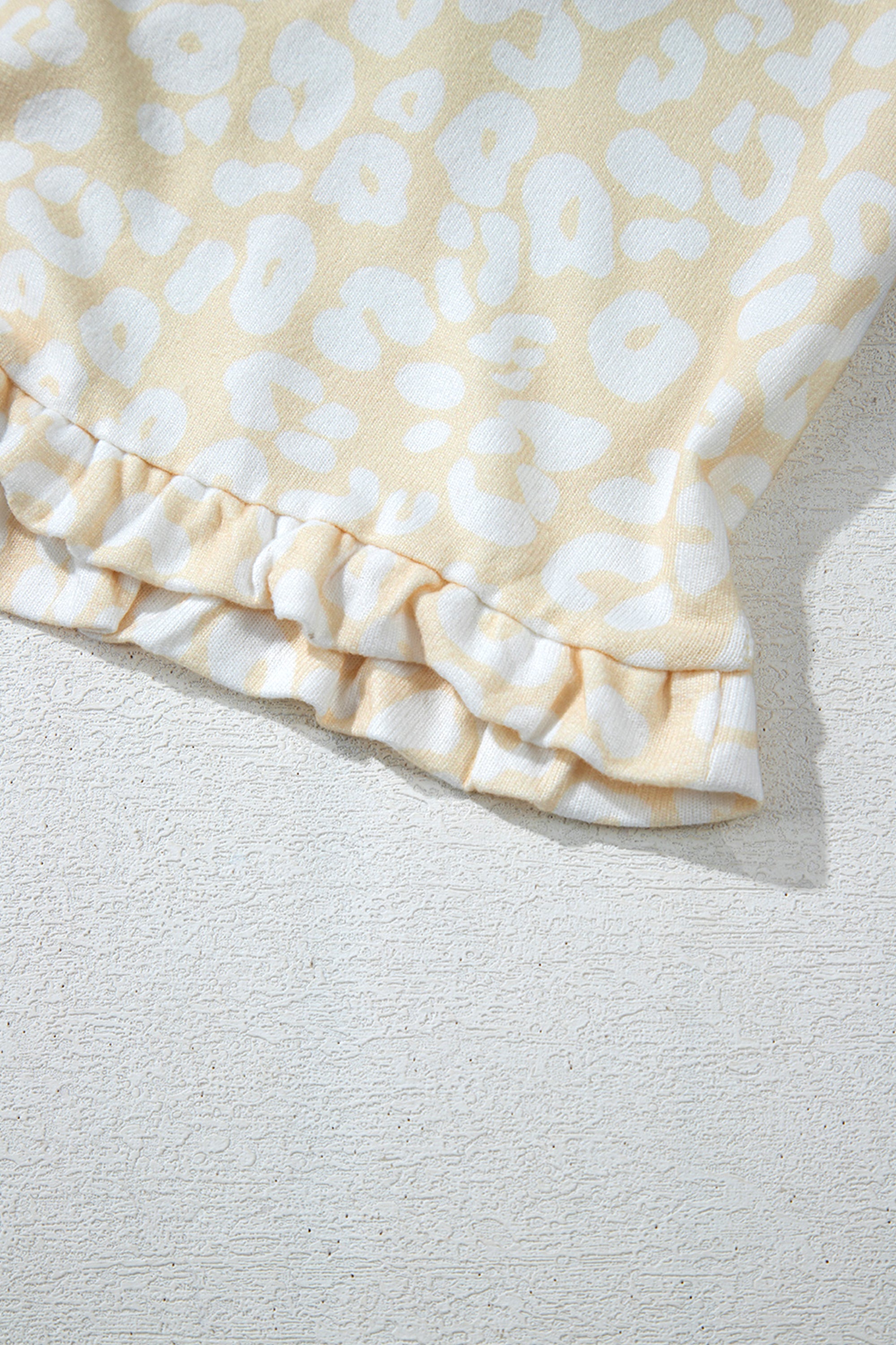 طقم نسائي قطعتين، مكون من بلوزة وبنطلون، لونه أبيض بنقشة الفهد باللون الذهبي المطفي. مصمم لراحتك بقصة فضفاضة وحزام خصر قابل للتعديل، ويتميز بتموجات جميلة على طرف البلوزة.