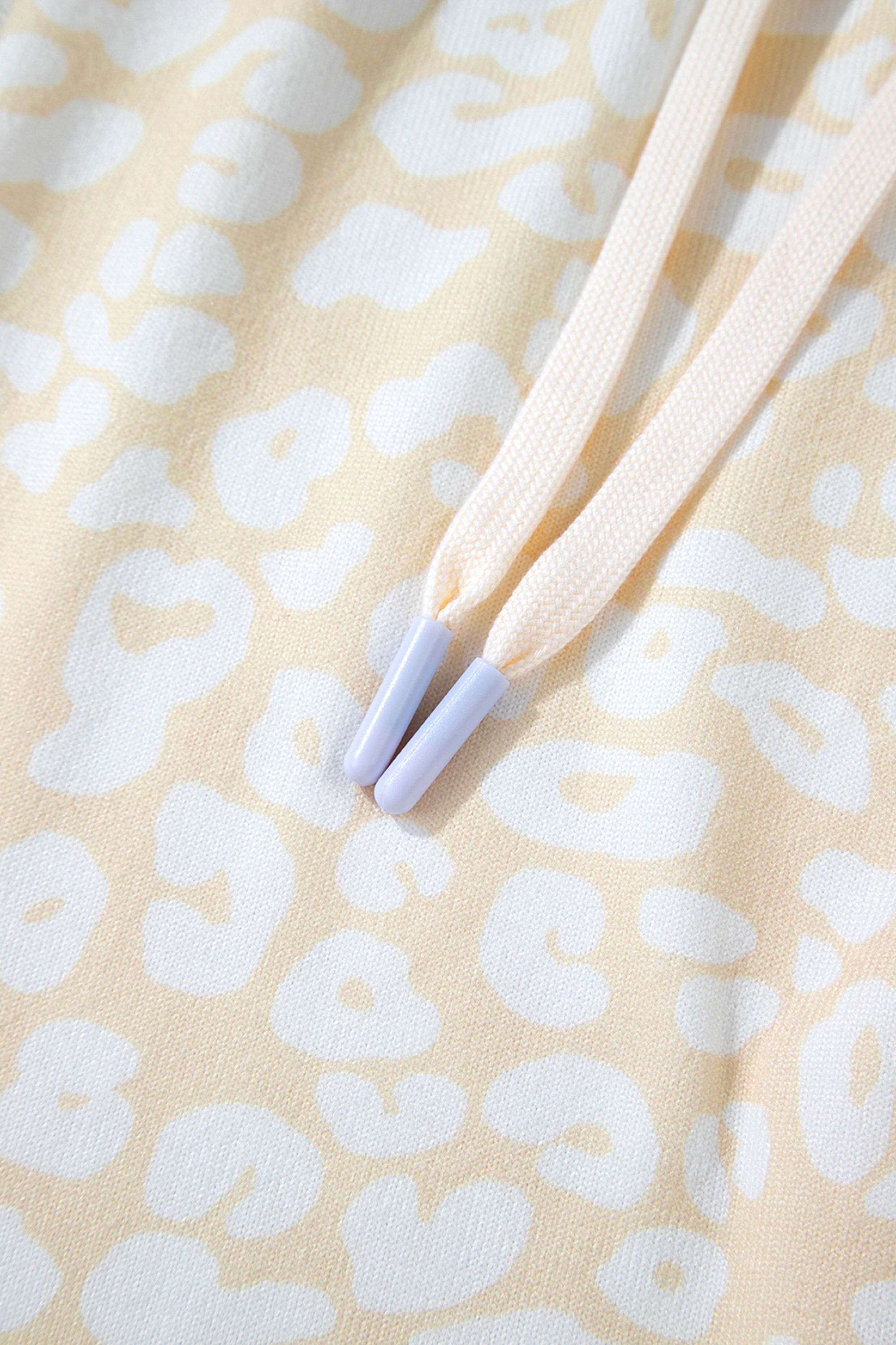 طقم نسائي قطعتين، مكون من بلوزة وبنطلون، لونه أبيض بنقشة الفهد باللون الذهبي المطفي. مصمم لراحتك بقصة فضفاضة وحزام خصر قابل للتعديل، ويتميز بتموجات جميلة على طرف البلوزة.