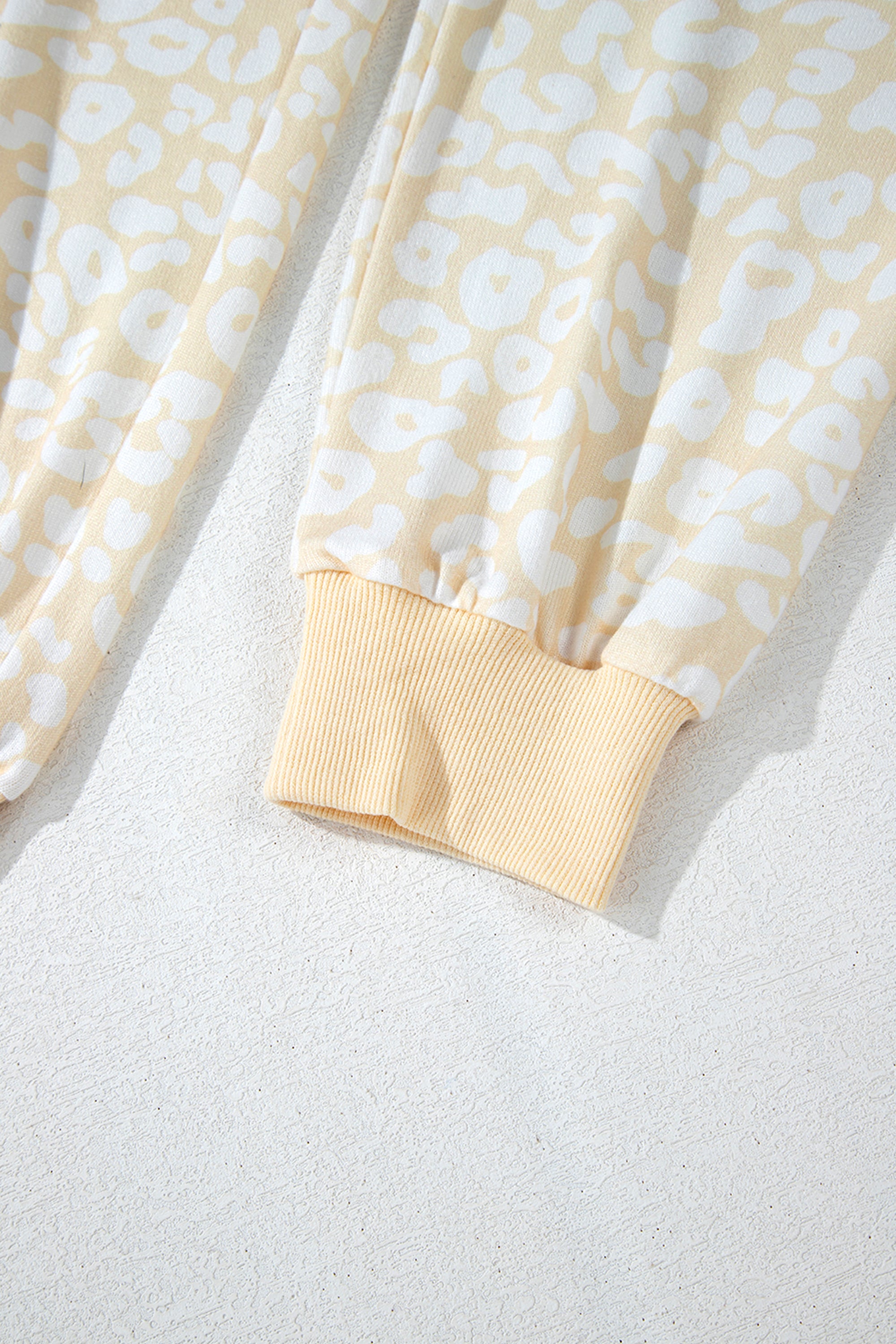 طقم نسائي قطعتين، مكون من بلوزة وبنطلون، لونه أبيض بنقشة الفهد باللون الذهبي المطفي. مصمم لراحتك بقصة فضفاضة وحزام خصر قابل للتعديل، ويتميز بتموجات جميلة على طرف البلوزة.