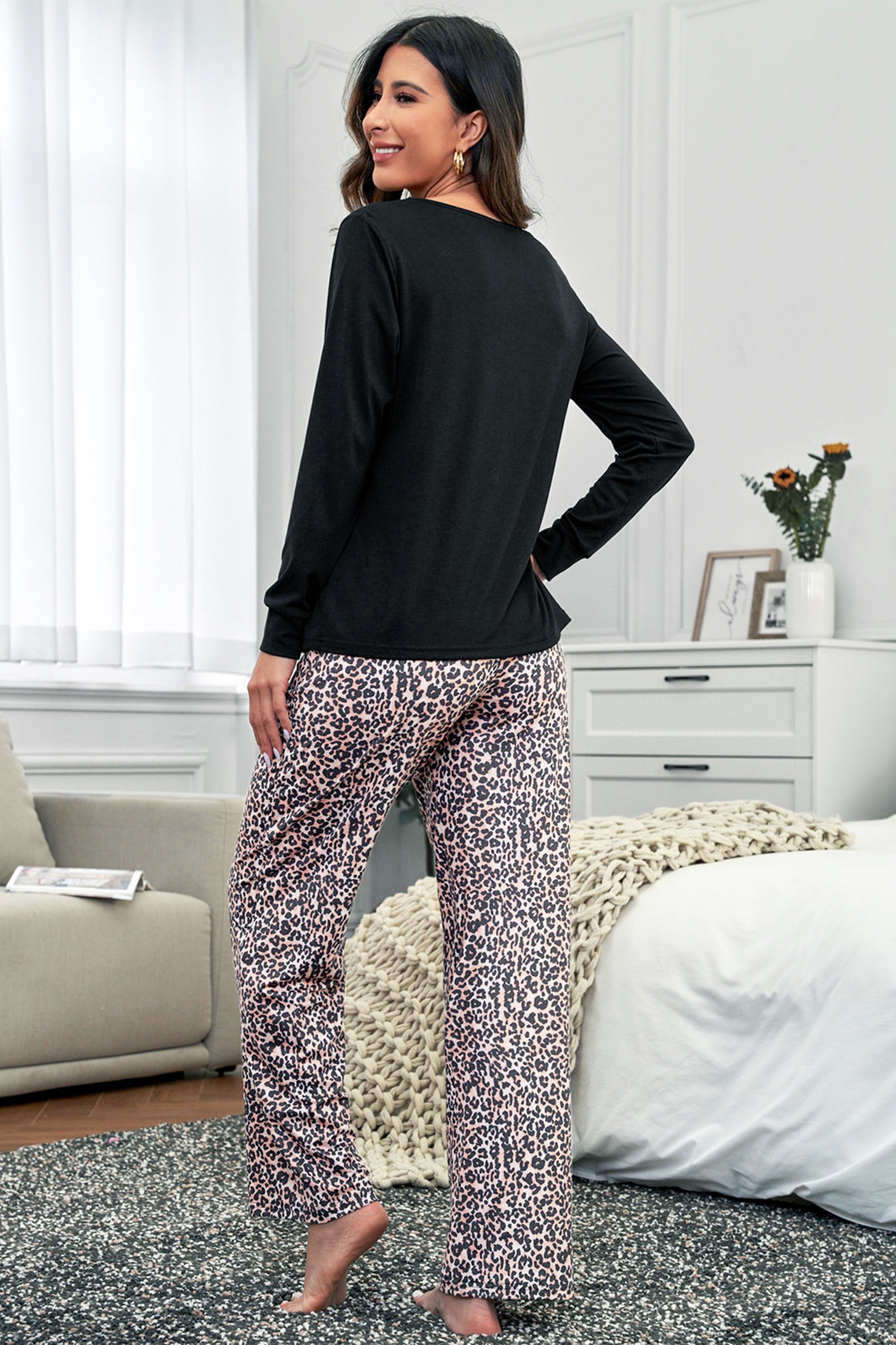 طقم ملابس بيت مكون من بلوزة لون اسود بأكمام طويلة ورقبة دائرية، مع بنطلون بطبعة جلد النمر لمظهر أنيق.
