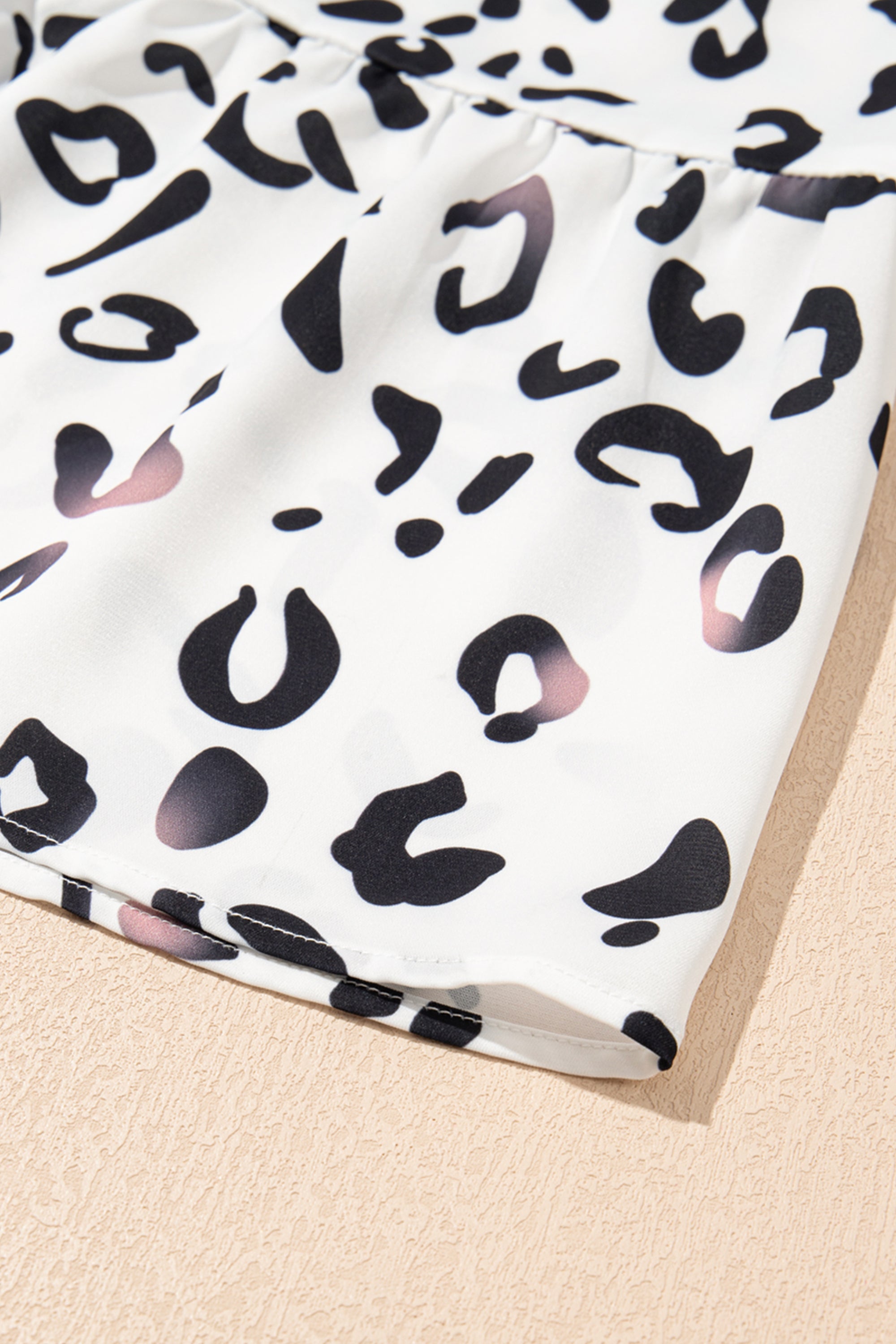 فستان طويل ابيض نقشة النمر. يتميز بتصميم أنيق وعصري، مع ياقة على شكل حرف V وأكمام مزمومة وقصة فضفاضة، بينما تضفي الطبقات على الطول الماكسي إطلالة مريحة وأكثر رشاقة وجاذبية.