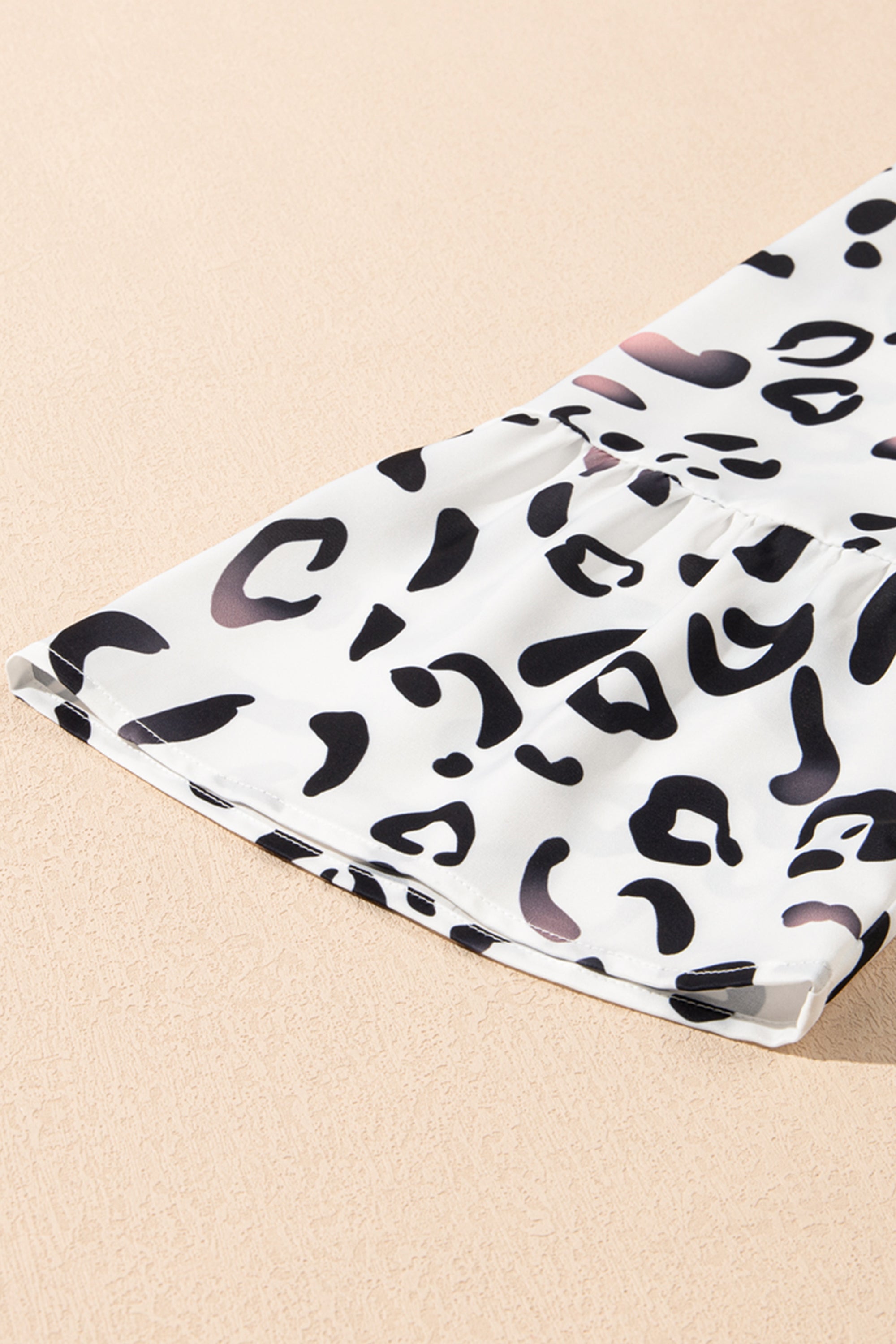 فستان طويل ابيض نقشة النمر. يتميز بتصميم أنيق وعصري، مع ياقة على شكل حرف V وأكمام مزمومة وقصة فضفاضة، بينما تضفي الطبقات على الطول الماكسي إطلالة مريحة وأكثر رشاقة وجاذبية.