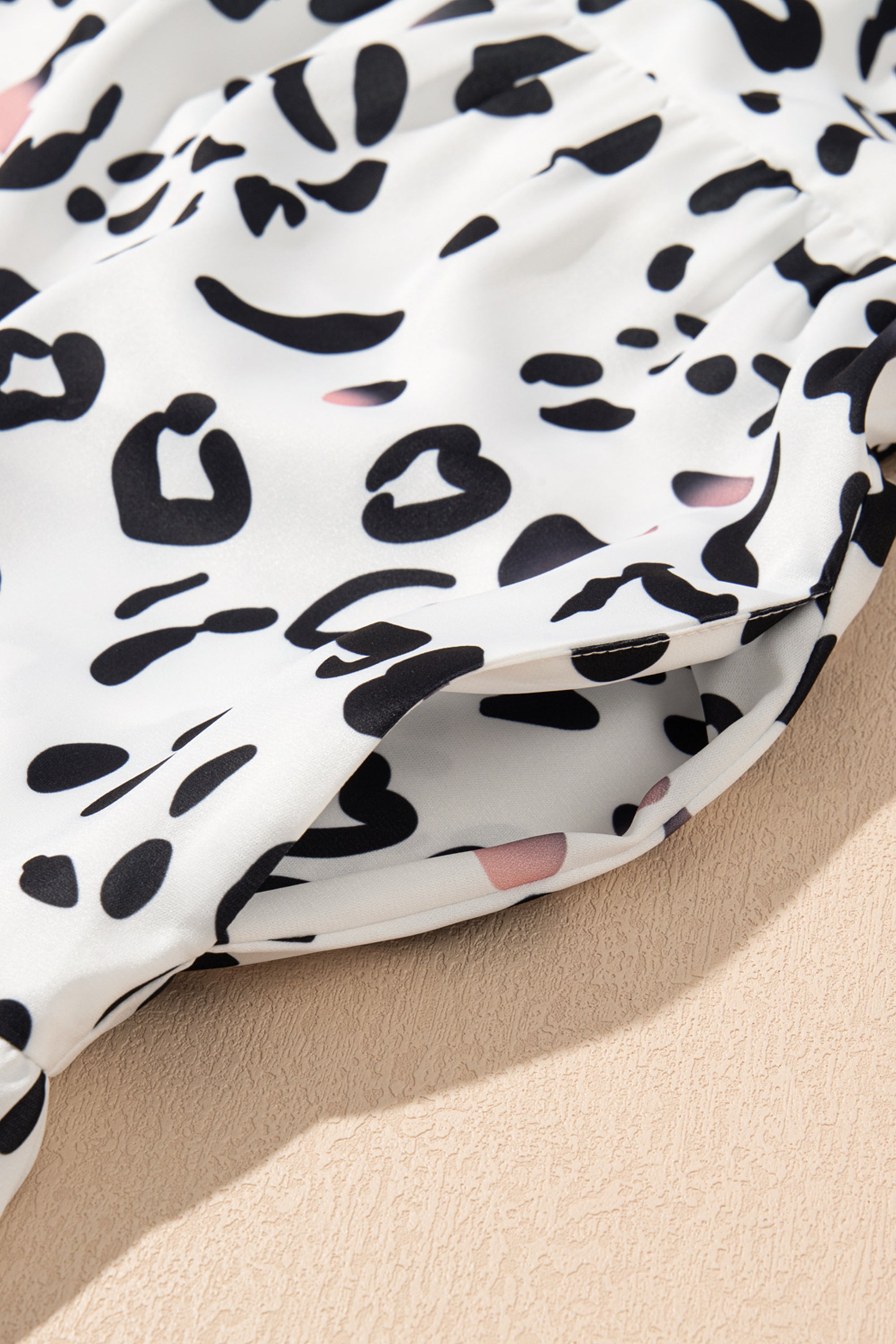 فستان طويل ابيض نقشة النمر. يتميز بتصميم أنيق وعصري، مع ياقة على شكل حرف V وأكمام مزمومة وقصة فضفاضة، بينما تضفي الطبقات على الطول الماكسي إطلالة مريحة وأكثر رشاقة وجاذبية.