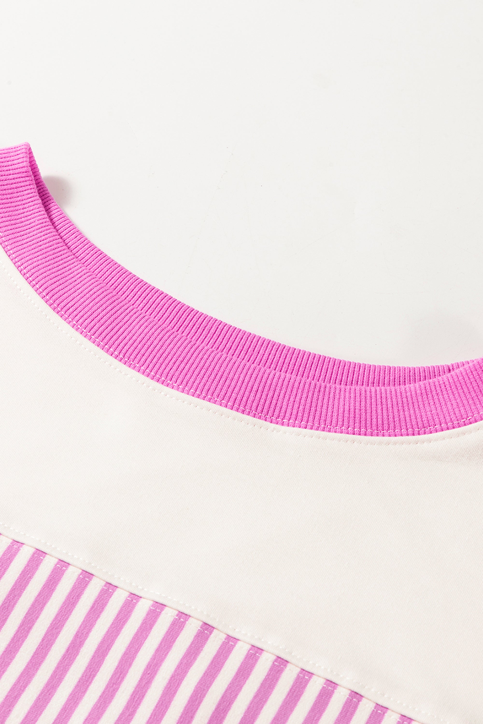 فستان تصميم واسع وجذاب يتميز بقماش مخطط باللونين الوردي والأبيض، ومصمم لإظهار تناسق الجسم. أكمام متوسطة الطول وياقة دائرية كلاسيكية.